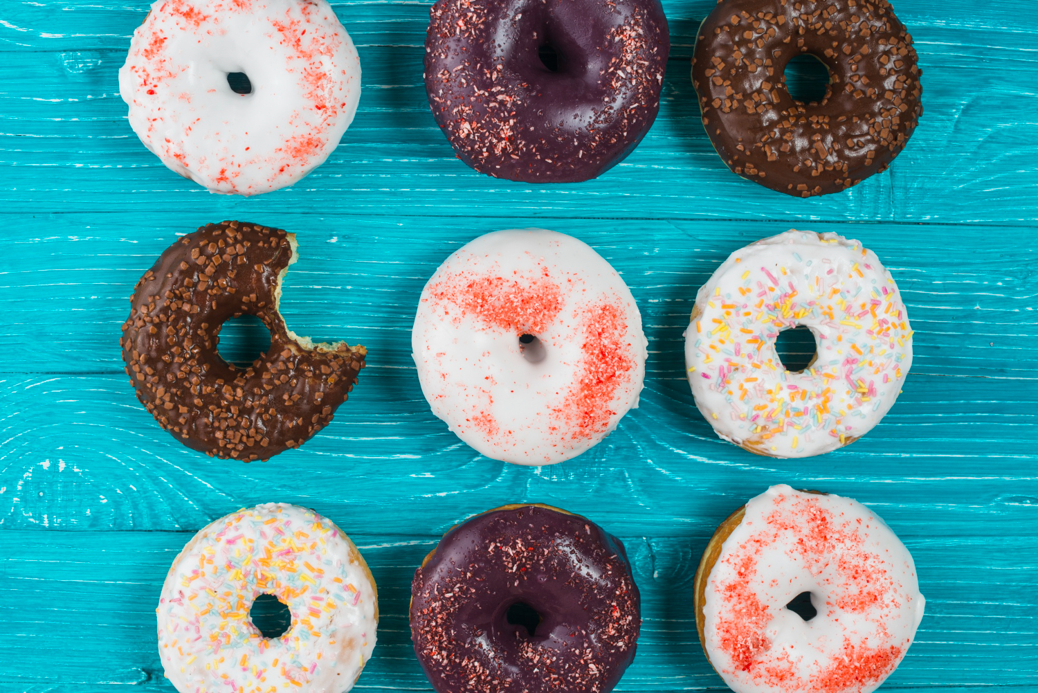 Nine different flavored donuts on a table.
